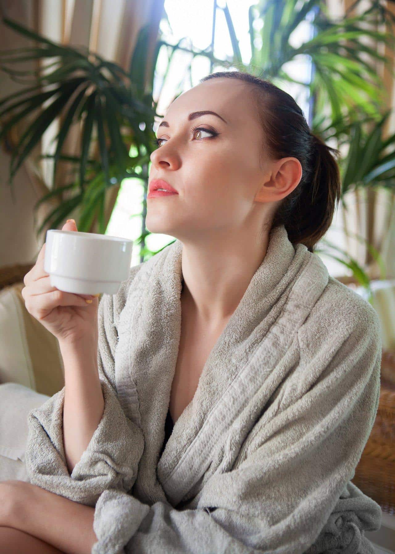 Une femme apaisée buvant une tisane lors d'une soirée relaxante pour optimiser sa cure détox.