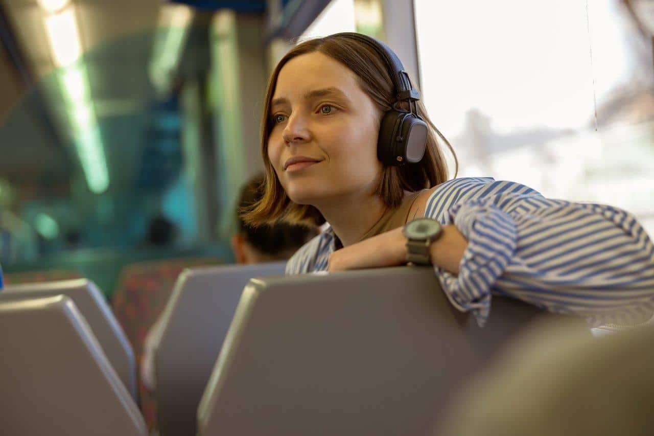 Une femme souriante pratique la commuter meditation pour un bien-être quotidien dans les transports.