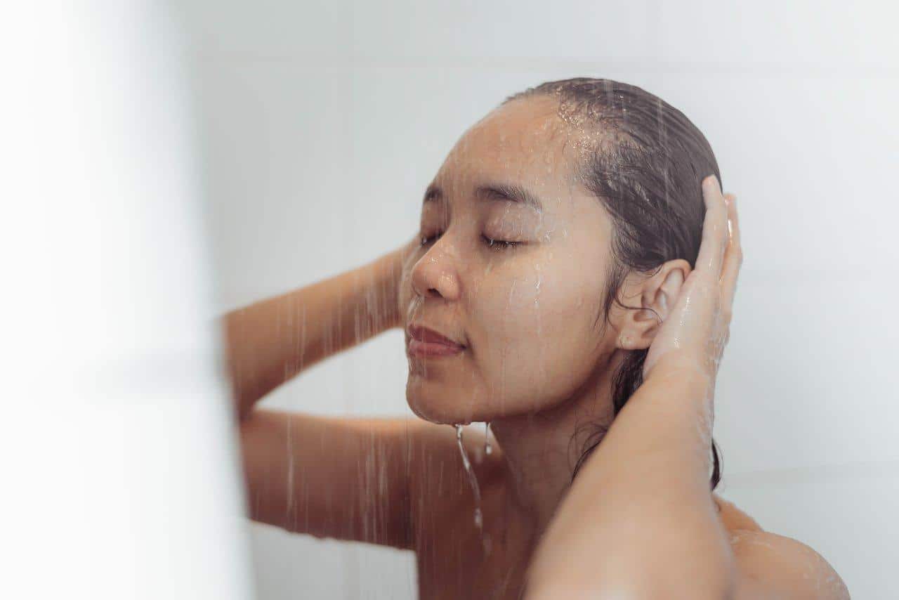 Femme rinçant ses cheveux avec de l’eau claire après la baignade pour protéger ses cheveux du soleil.