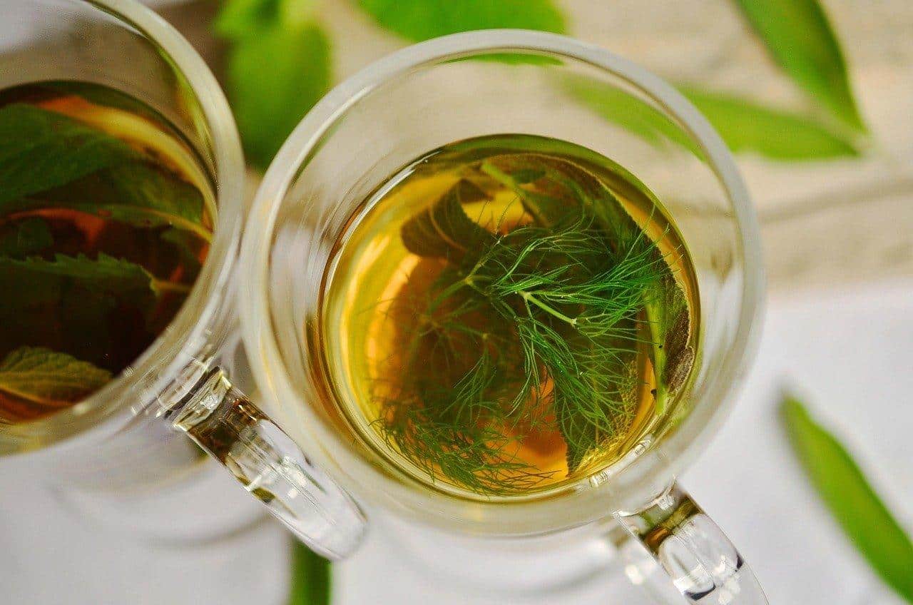 Tasse de peppermint herbal tea, idéale pour soulager la digestion difficile, entourée de feuilles de menthe fraîches.