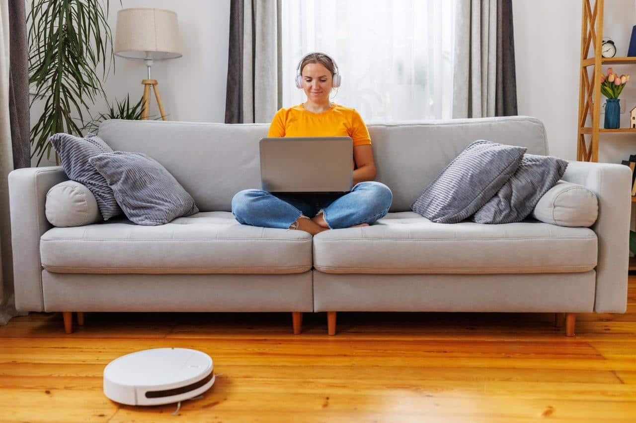 Un robot vacuum cleaning the living room, illustrant l'automatisation pour gagner du temps dans le ménage.