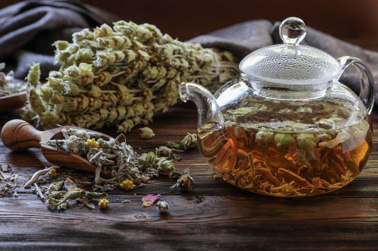 Infusion de plantes médicinales pour réguler les règles abondantes, avec framboisier et sauge sur une table chaleureuse.
