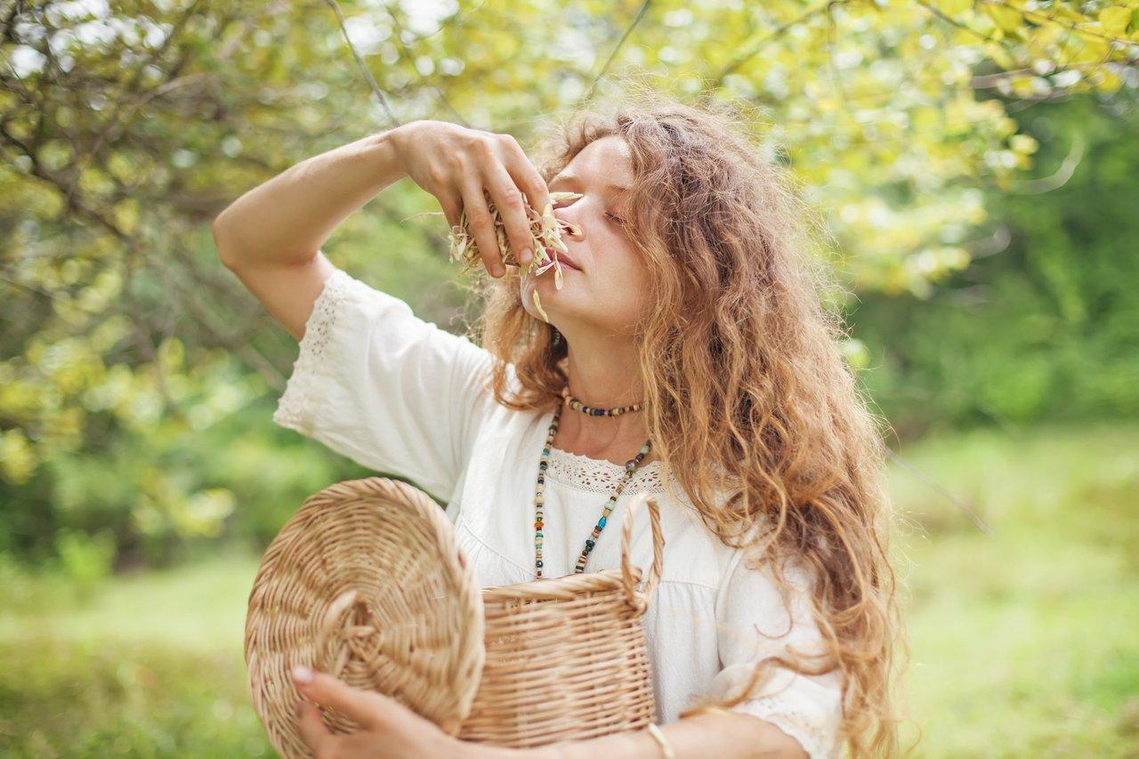 Femme pratiquant le yoga en nature avec un panier d'herbes et fruits frais, idéale pour la phytothérapie saisonnière.