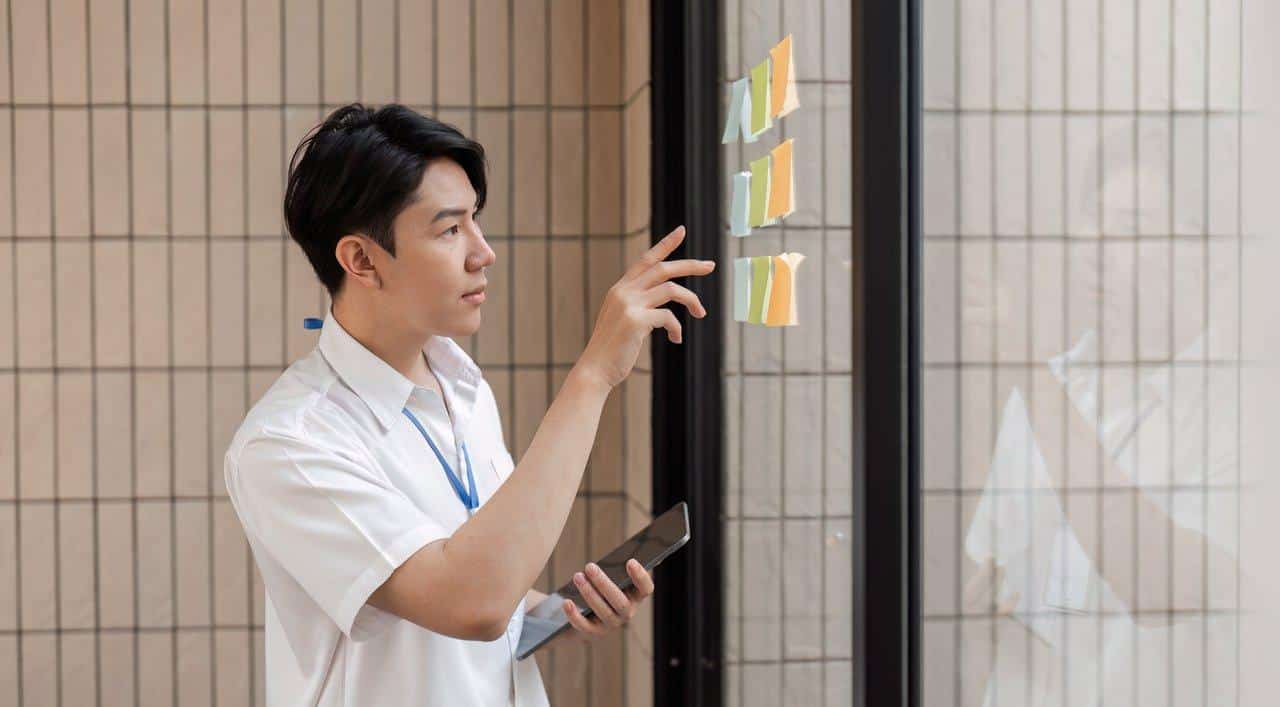 Personne en pleine revue hebdomadaire devant un tableau Kanban pour gérer efficacement ses projets personnels.