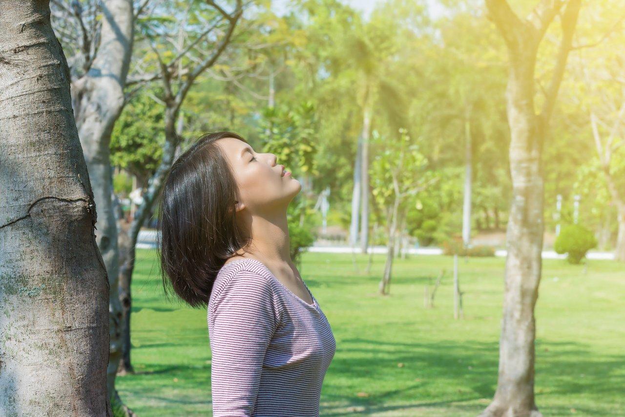 Une femme pratiquant la respiration diaphragmatique dans la nature pour une détox émotionnelle apaisante.