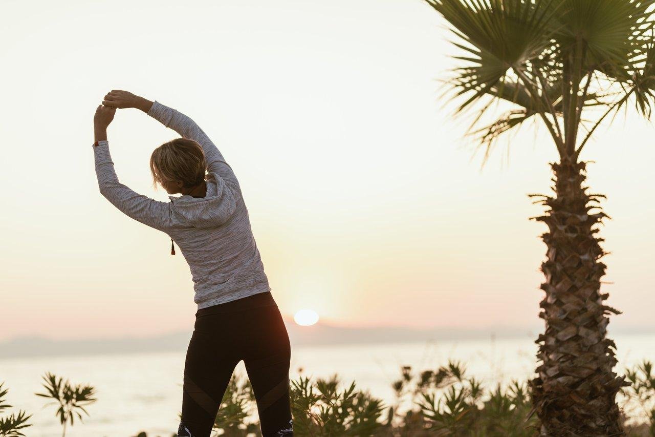 Une femme de 40 ans pratiquant le yoga au lever du soleil près de la plage, pour un bien-être optimal.